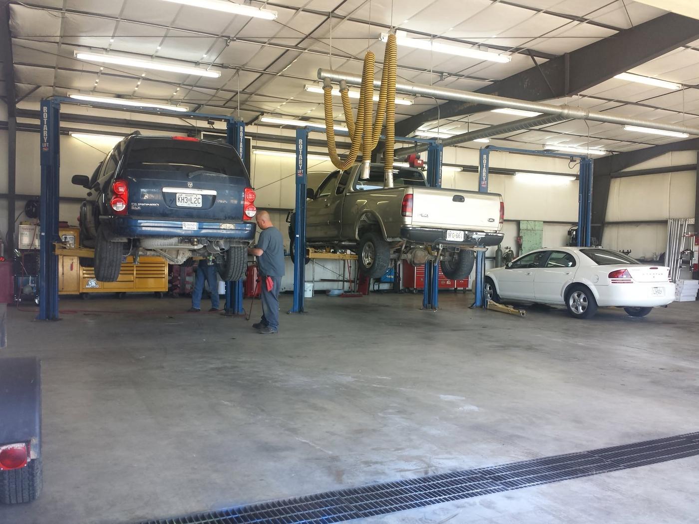 Vehicles raised on lifts inside the workshop with technicians at work
